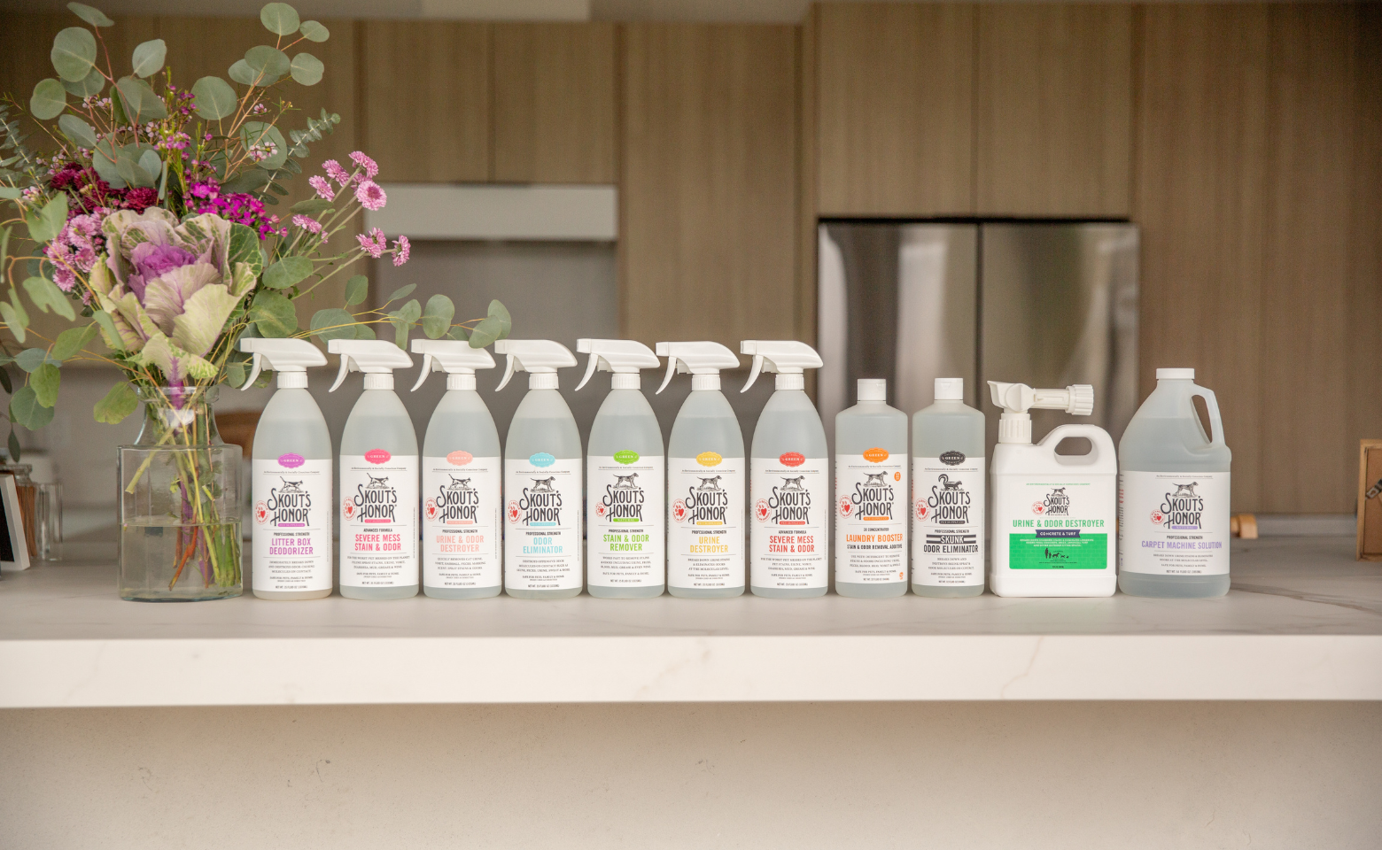 A row of Skout's Honor cleaning products on countertop with flowers